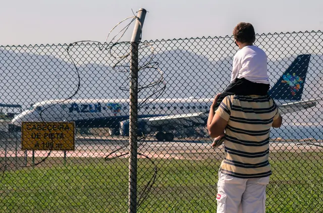 Father carrying his son on his shoulders, watching an aircraft